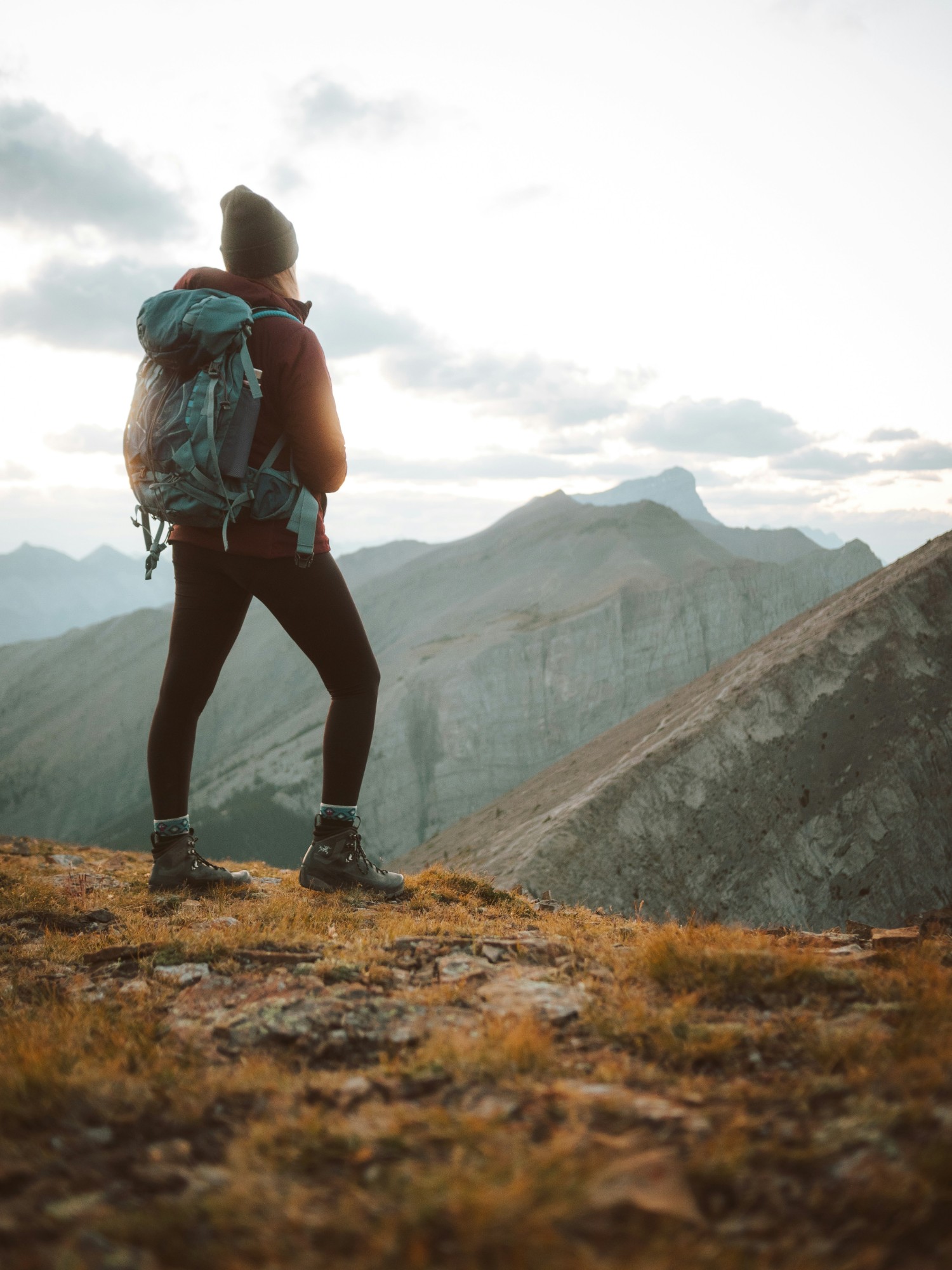 A hiker on a mountain ridge at sunrise, looking out over the valley